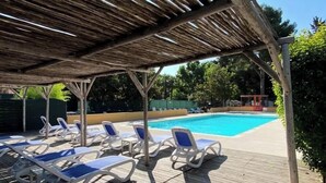 A covered pool area with lounge chairs and a clear blue pool. - LE COCON DE L'ARNEL (Villeneuve-lès-Maguelone)