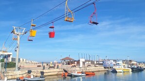 A coastal area with a cable car system, boats docked at a marina, and a clear blue sky. - LE COCON DE L'ARNEL (Villeneuve-lès-Maguelone)