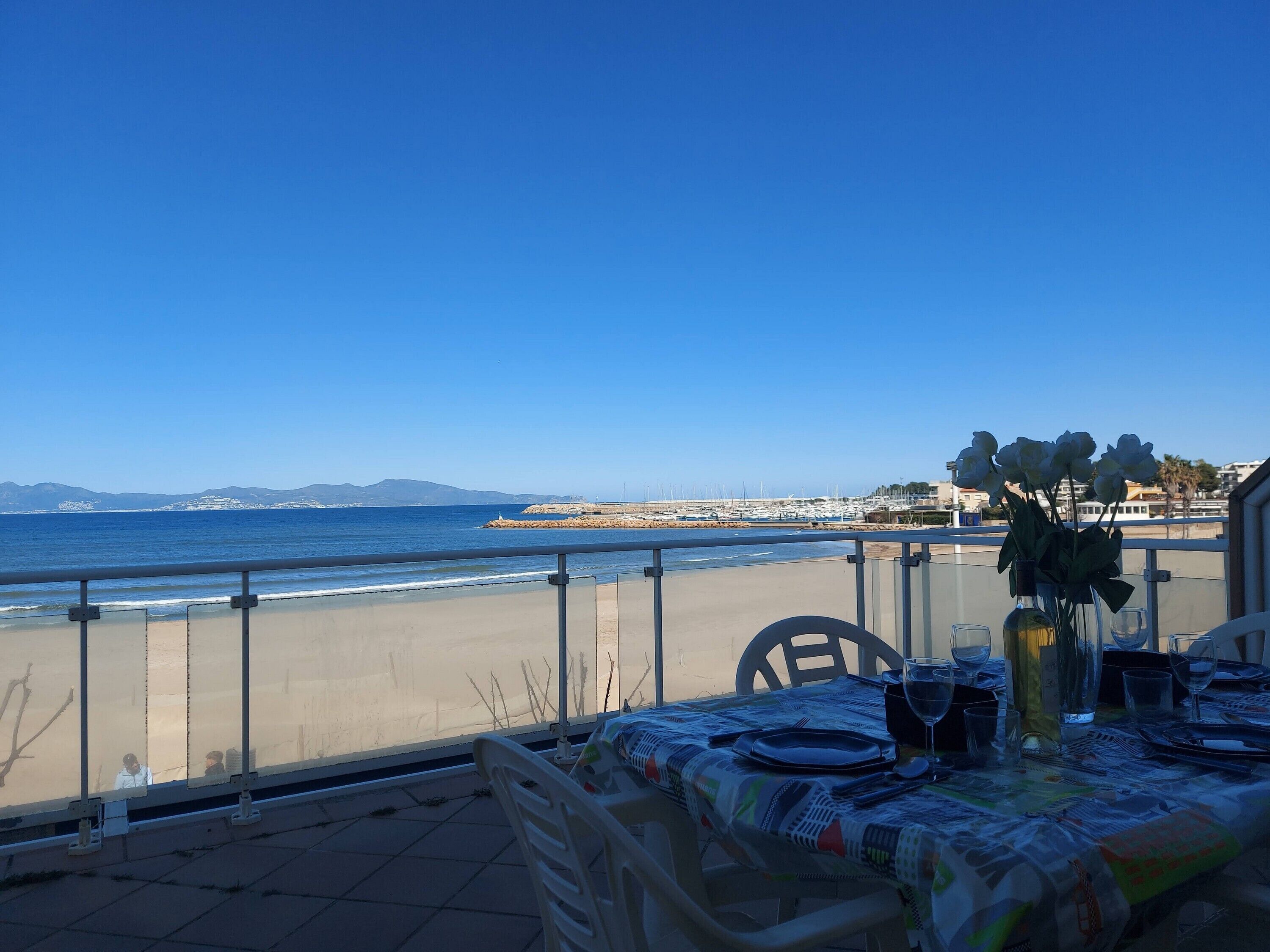 A table set for dining with a view of the sea and distant mountains.
