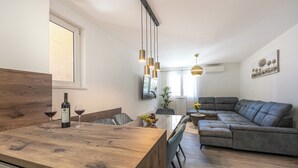 A modern living space with a wooden dining table, a grey sofa, and pendant lighting. - Stylish apartment with terrace and private parking space in Crikvenica (Crikvenica)