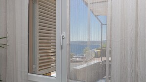A window with white blinds, a mesh screen, and a view of a building and a car outside. - Stylish apartment with terrace and private parking space in Crikvenica (Crikvenica)