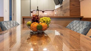 A wooden dining table with a fruit bowl in the center, two chairs, and a kitchen in the background. - Stylish apartment with terrace and private parking space in Crikvenica (Crikvenica)