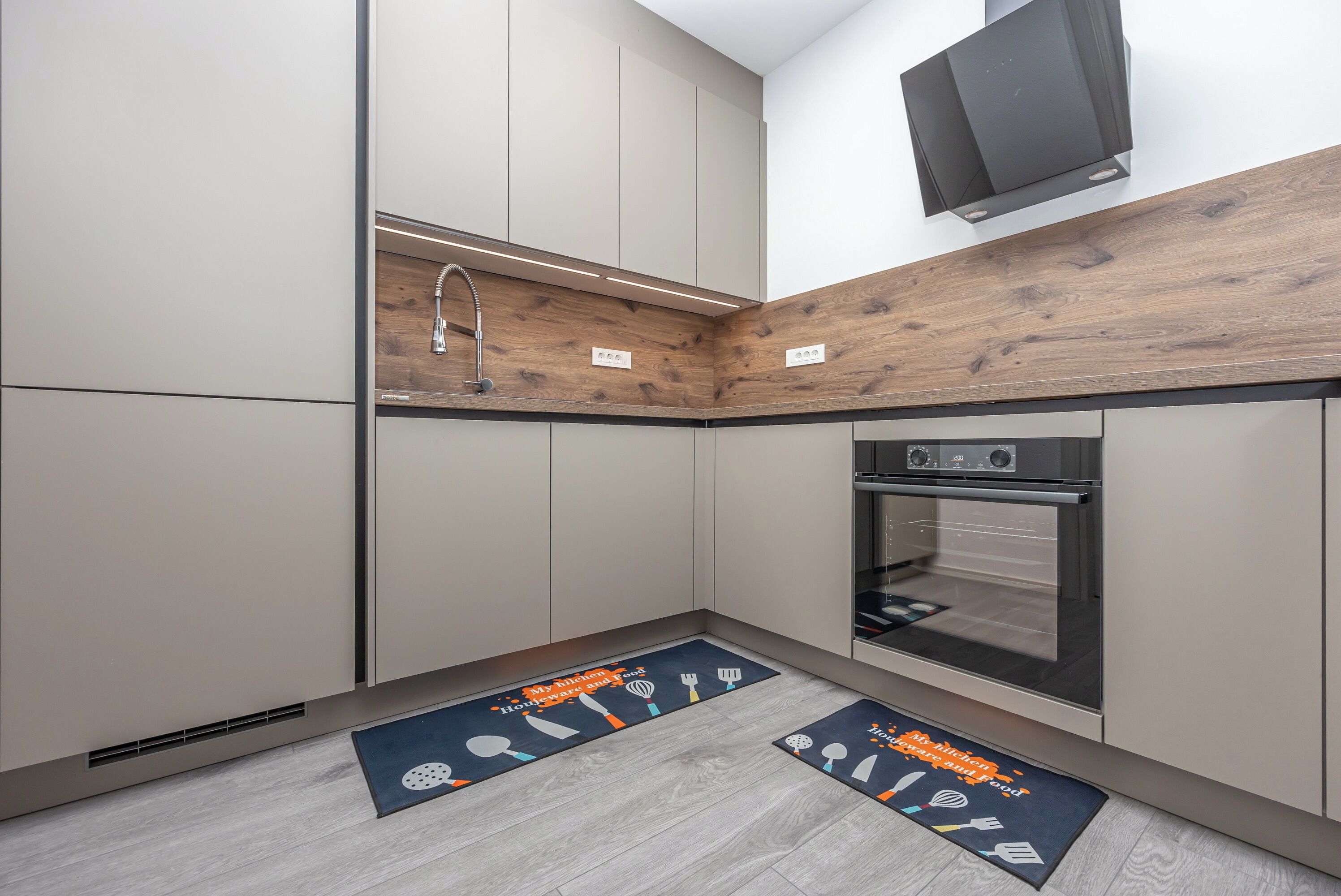 Eine moderne Küche mit Einbauofen, einer Wand in Holzoptik und einer Kücheninsel mit Spüle.