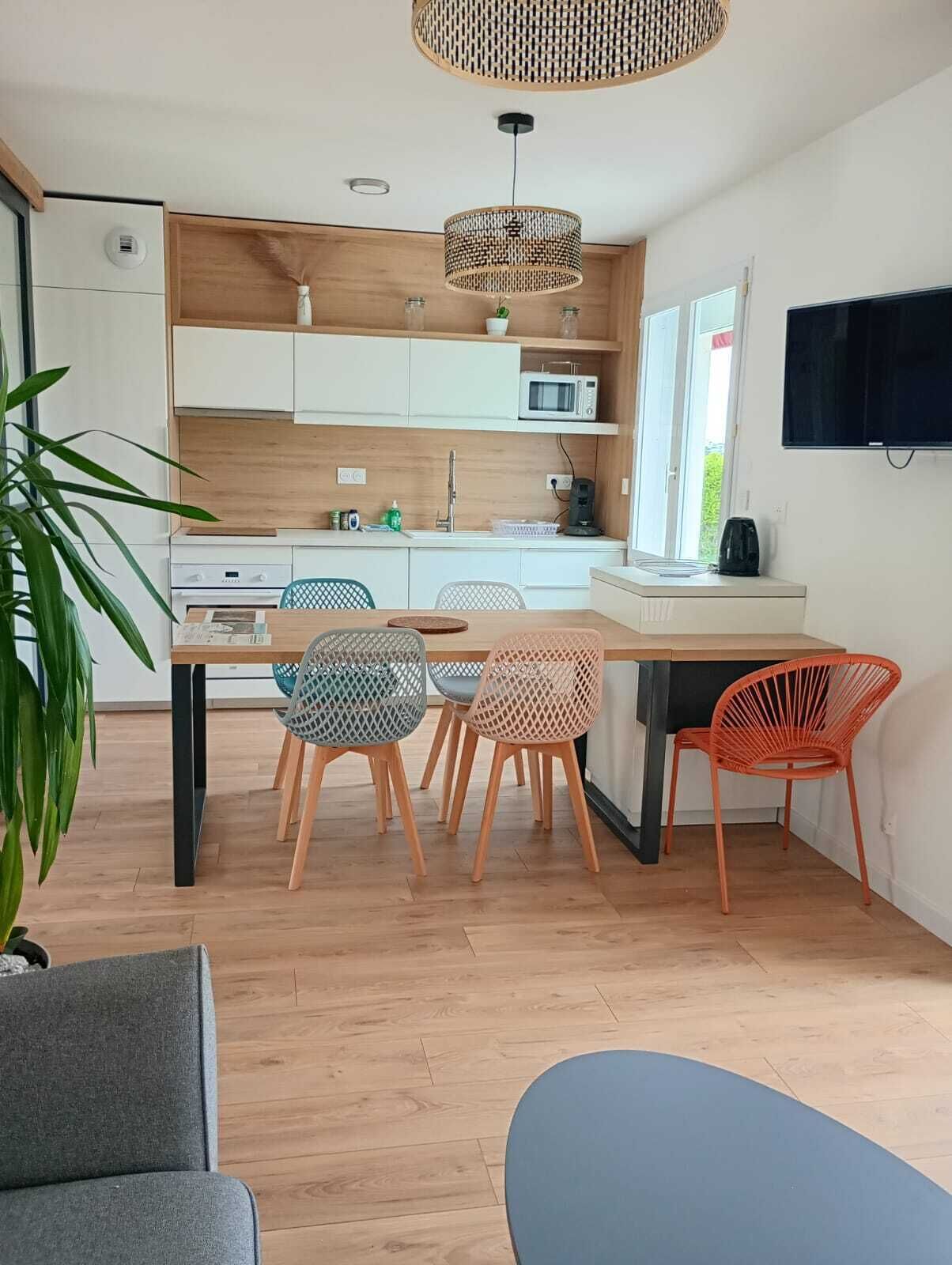 A modern kitchen with white cabinets, a microwave, and a dining area with a table and chairs.