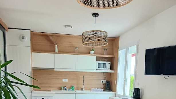 A modern kitchen with white cabinets, a microwave, and a dining area with a table and chairs.