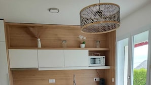 A modern kitchen with white cabinets, a wooden countertop, a microwave, and a dining area with a table and chairs.