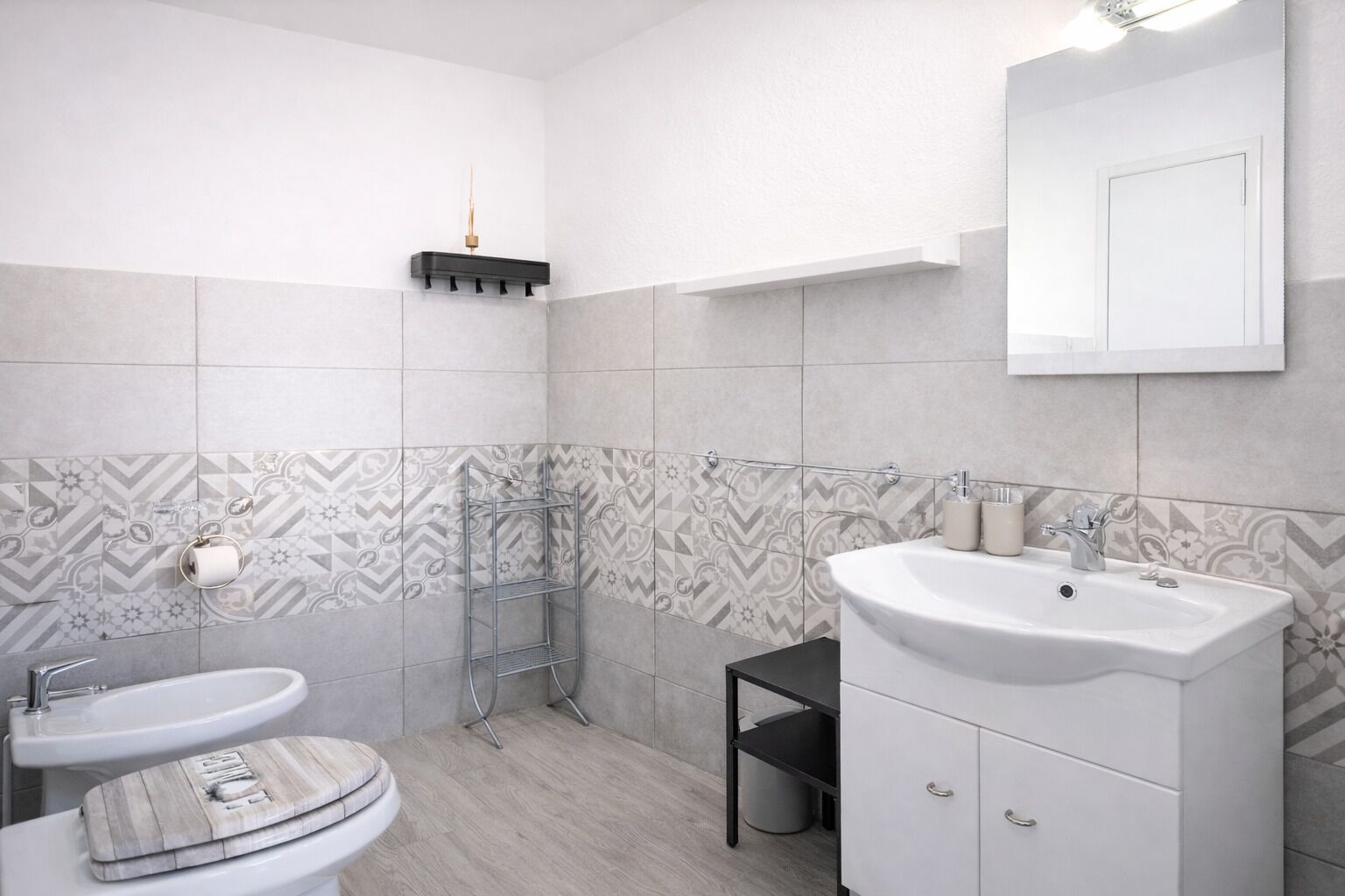 A bathroom with two sinks, a mirror, a towel rack, and patterned tiles.