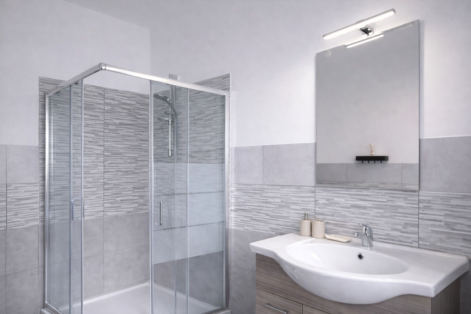 A modern bathroom with a glass shower enclosure, a white sink, and a large mirror.