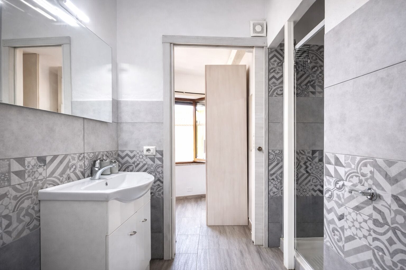 A modern bathroom with a sink, mirror, and shower area.