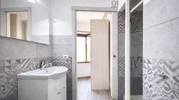 A modern bathroom with a sink, mirror, and shower area.