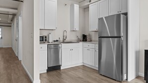 Una cocina moderna con armarios blancos, electrodomésticos de acero inoxidable y piso de madera.