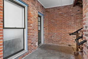 A room with a brick wall, a door, and a window with blinds. - 2BR on Historic Main | Free Parking (Saint Charles)