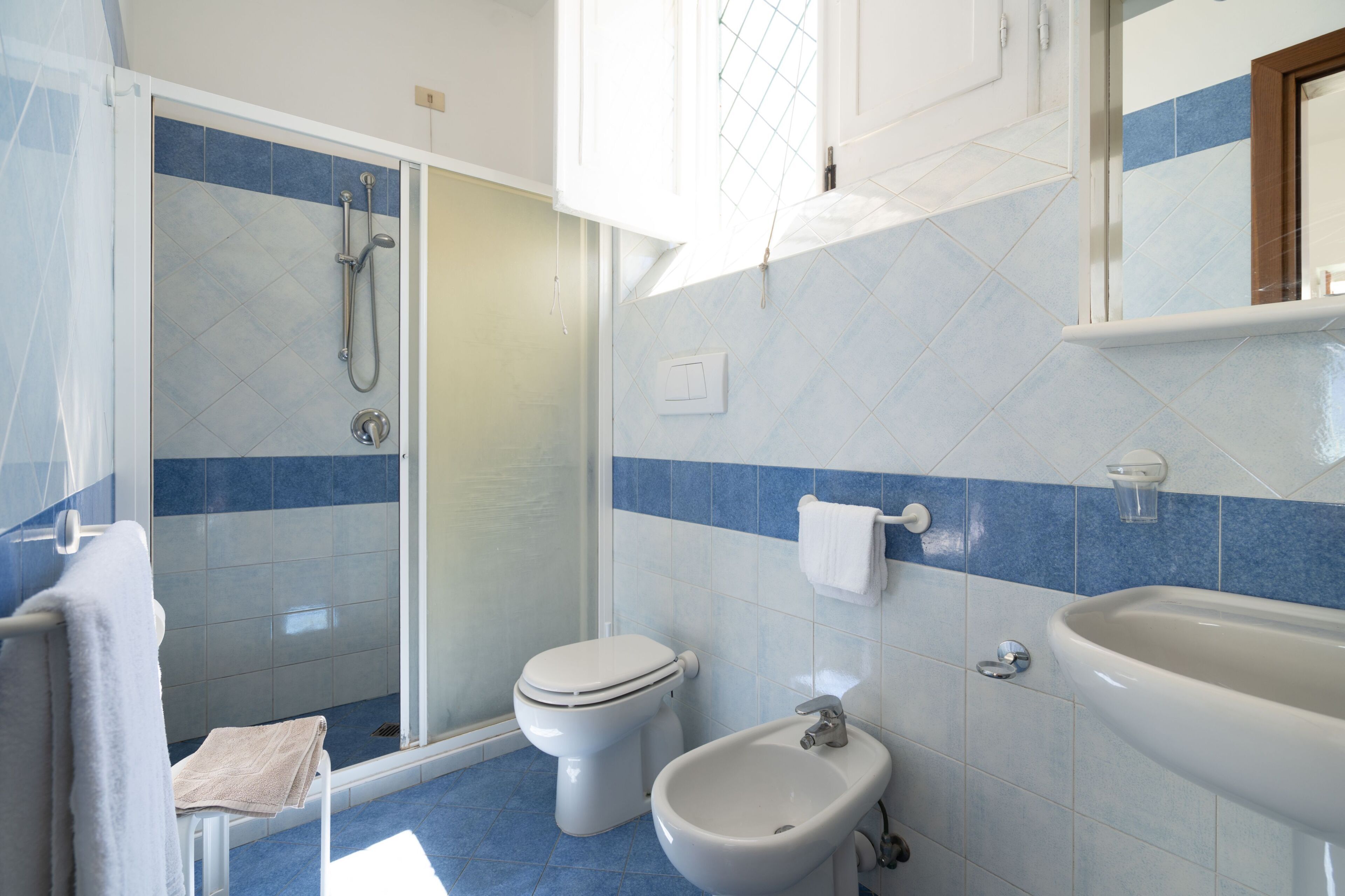 Une salle de bain équipée d’une douche, de toilettes, d’un bidet et d’un lavabo.