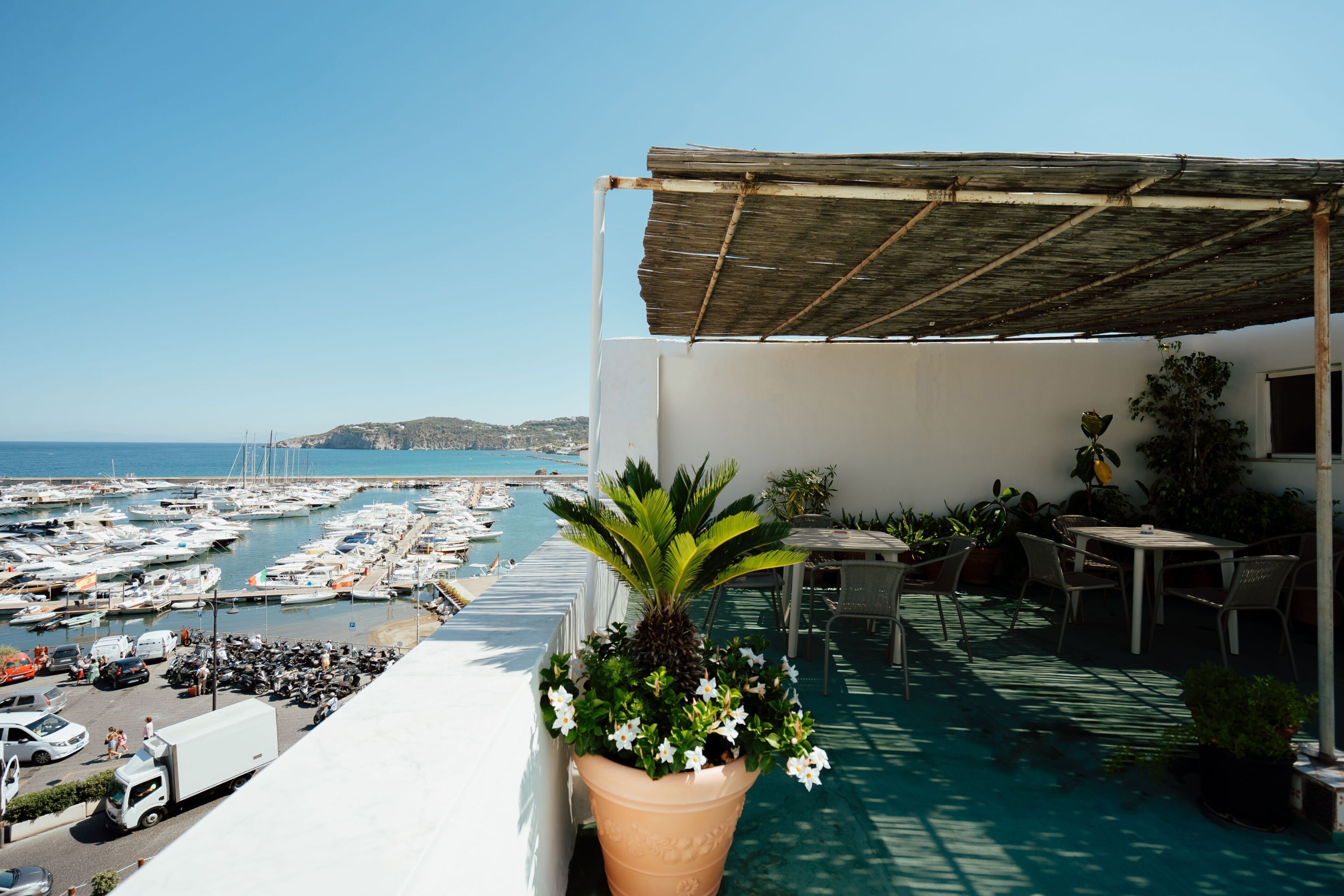 Une terrasse avec vue sur un port de plaisance, des sièges extérieurs et un pot de fleurs.