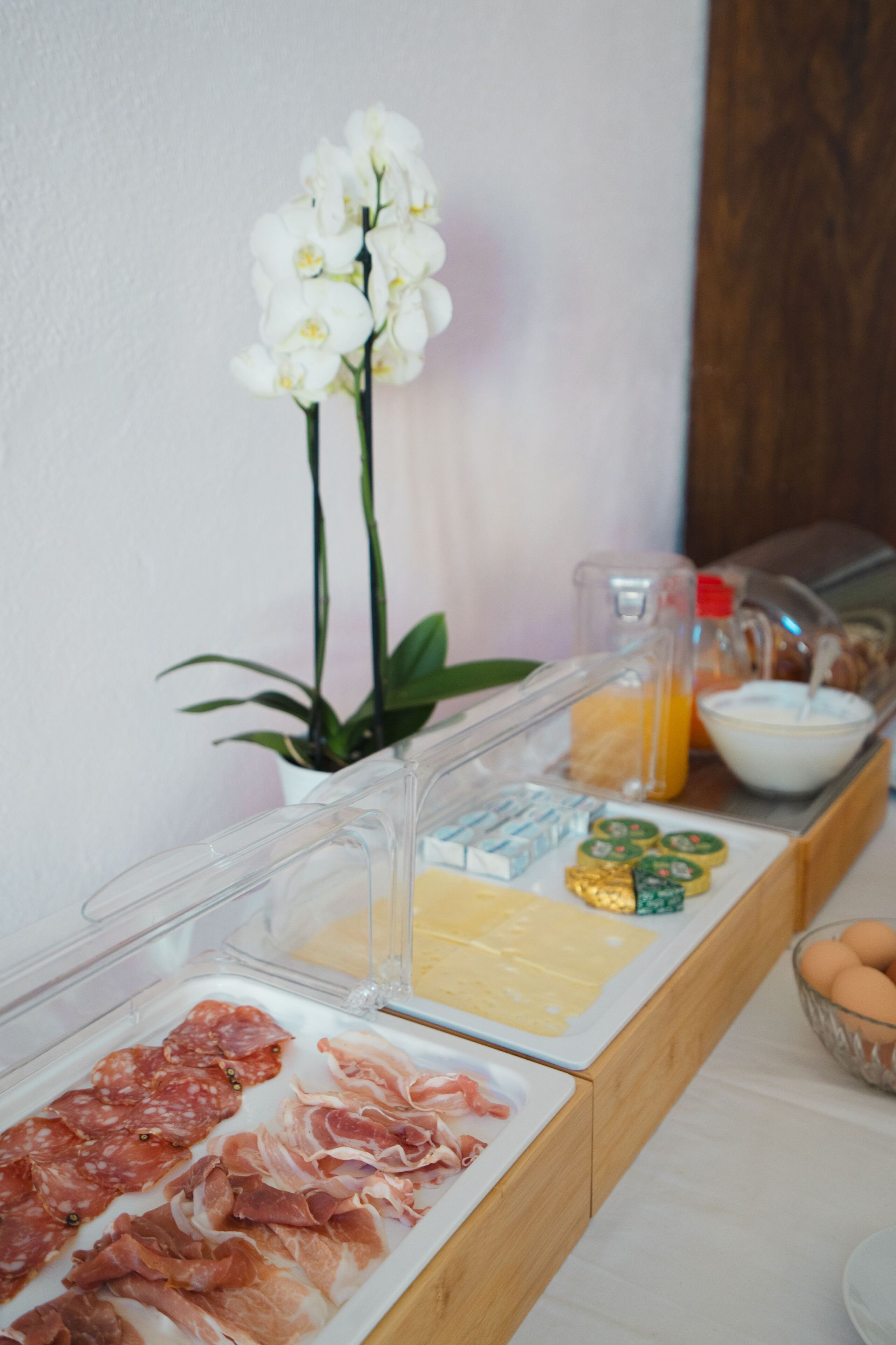 A breakfast buffet with various meats, cheeses, and condiments.