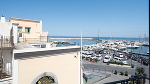 A marina with boats, a clear sky, and a building with a balcony.