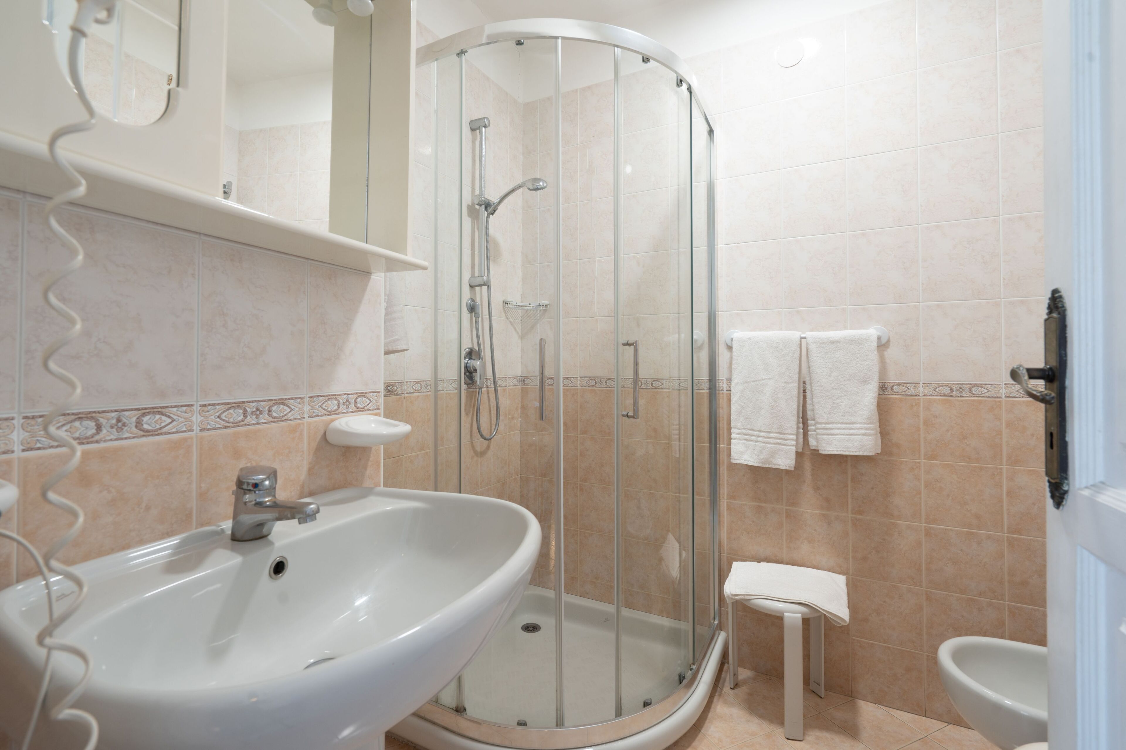 Un baño con ducha de vidrio, lavamanos, inodoro y espejo.