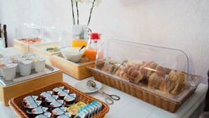A breakfast buffet with various food items, including pastries, yogurt, and juice.