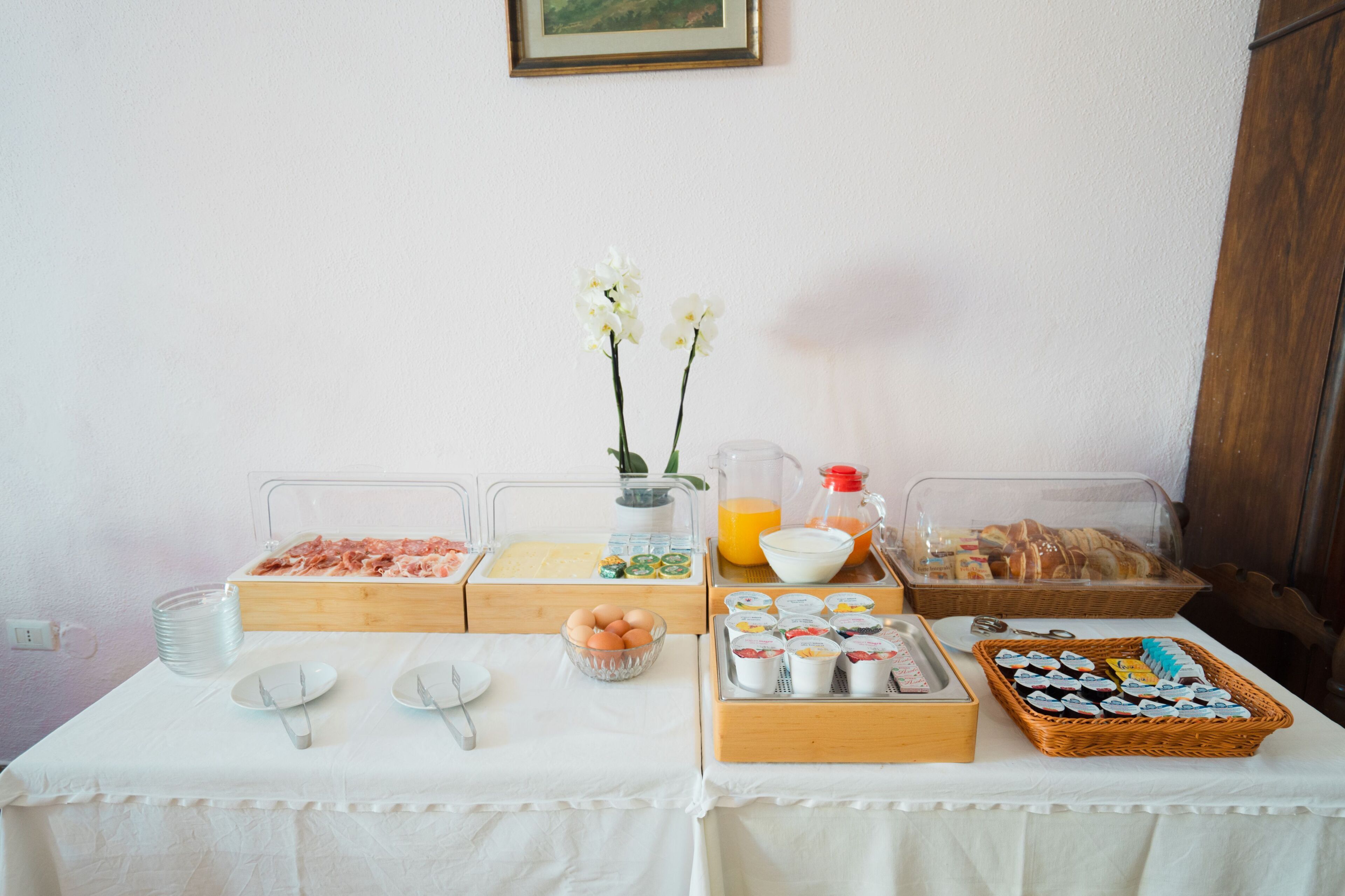 Un bufé de desayuno con diversas opciones de comida y un jarrón de flores blancas.