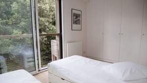 A bedroom with a large window, a bed, and a wardrobe.