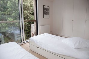 A bedroom with a large window, a bed, and a wardrobe.