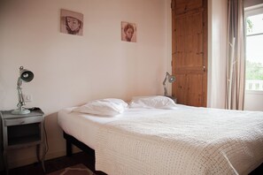 Ein Schlafzimmer mit einem Bett, zwei Nachttischlampen und zwei an der Wand befestigten Bildern.