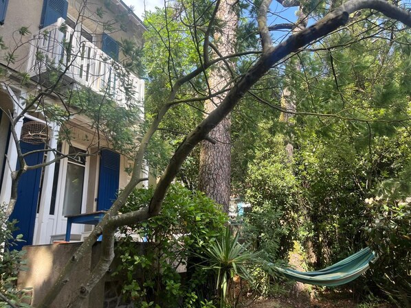 A hammock in a lush garden area with a building in the background. - Villa pornichetaine - Beach, station & center on foot- 7 people (Pornichet)