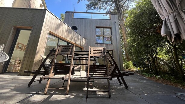 A modern building with a wooden deck and outdoor seating.