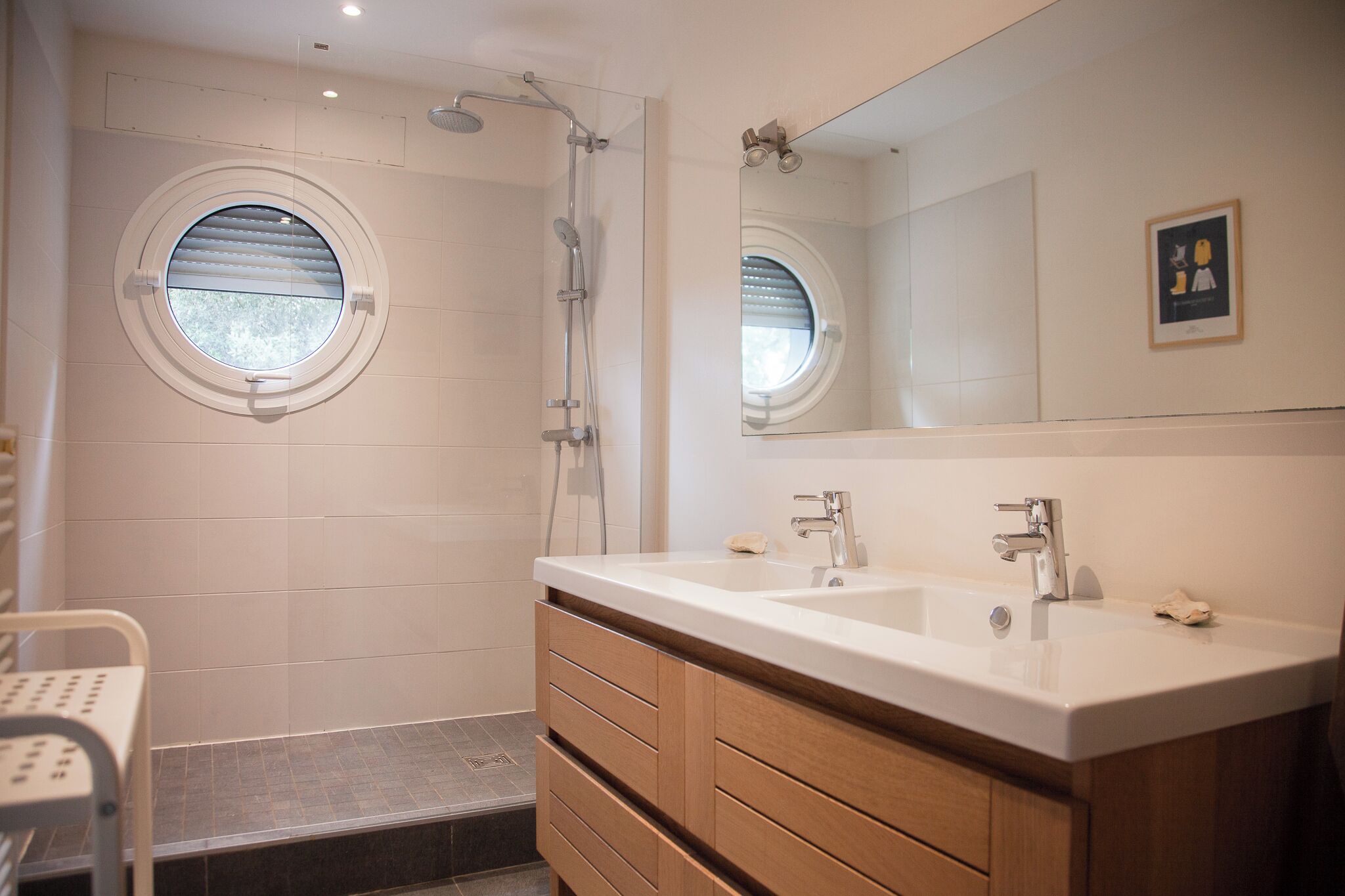 A bathroom with a shower, two sinks, a mirror, and a window.
