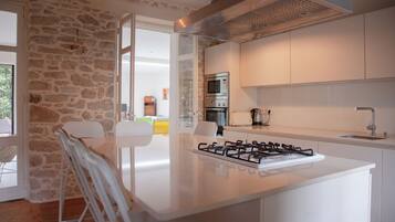 A modern kitchen with a gas stove, built-in oven, and a stone wall.