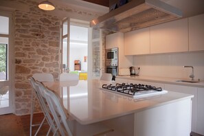 A modern kitchen with a gas stove, built-in oven, and a stone wall.