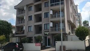 A multi-story building with balconies, a car parked in front, and signs for 'EMLAK MARKET' and 'ACAR APARTMENT.' - kasapoglu ceren pansiyon  (Bursa)