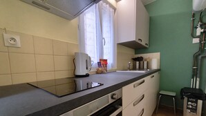 Une cuisine compacte équipée d’un four encastré, d’une bouilloire et d’un petit évier.