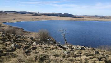Eine natürliche Landschaft mit Wasserfläche, felsigem Gelände und vereinzelter Vegetation.