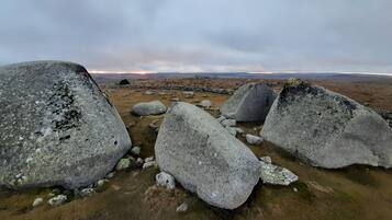 Eine felsige Landschaft mit großen Felsen und einem weiten Blick auf einen Sonnenuntergang.