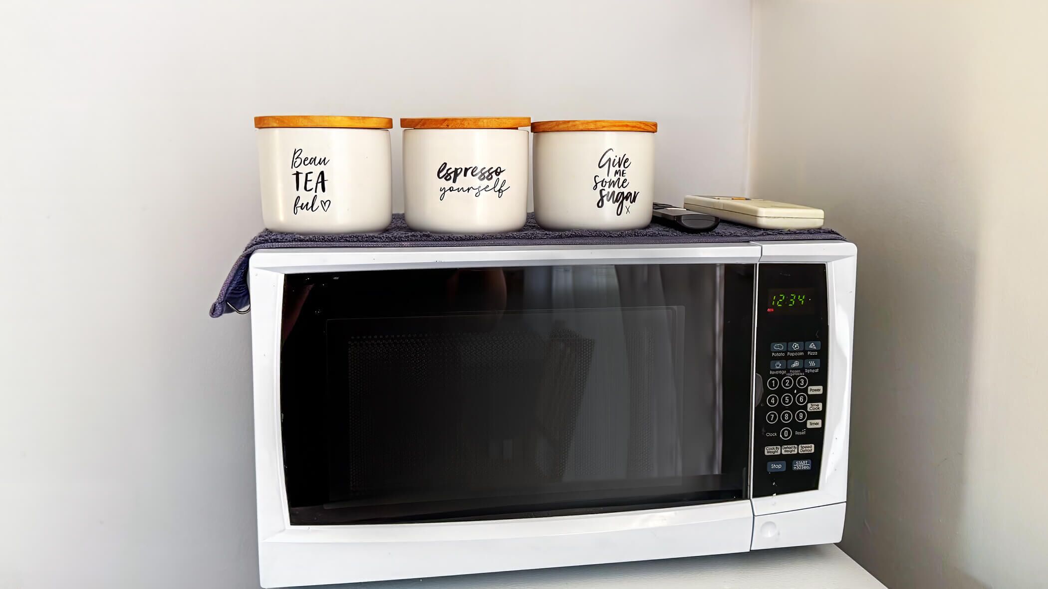 A microwave with three containers on top, each with a different motivational phrase.