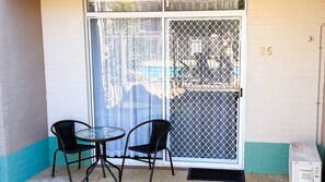 A small outdoor seating area with two chairs and a table, a sliding glass door with a metal screen, and a number '26' on the wall. - Pool View Studio | 3 Min Walk to Beach | Marina & Foreshore (Mandurah)