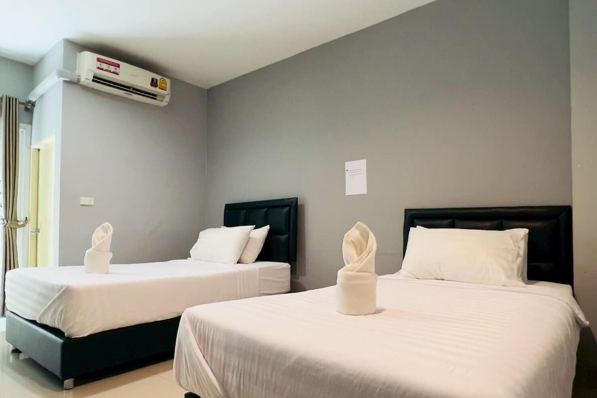 Two single beds with dark headboards, white linens, and towels folded on the beds.