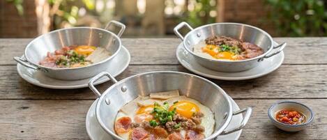 Three metal bowls with food on a wooden table.