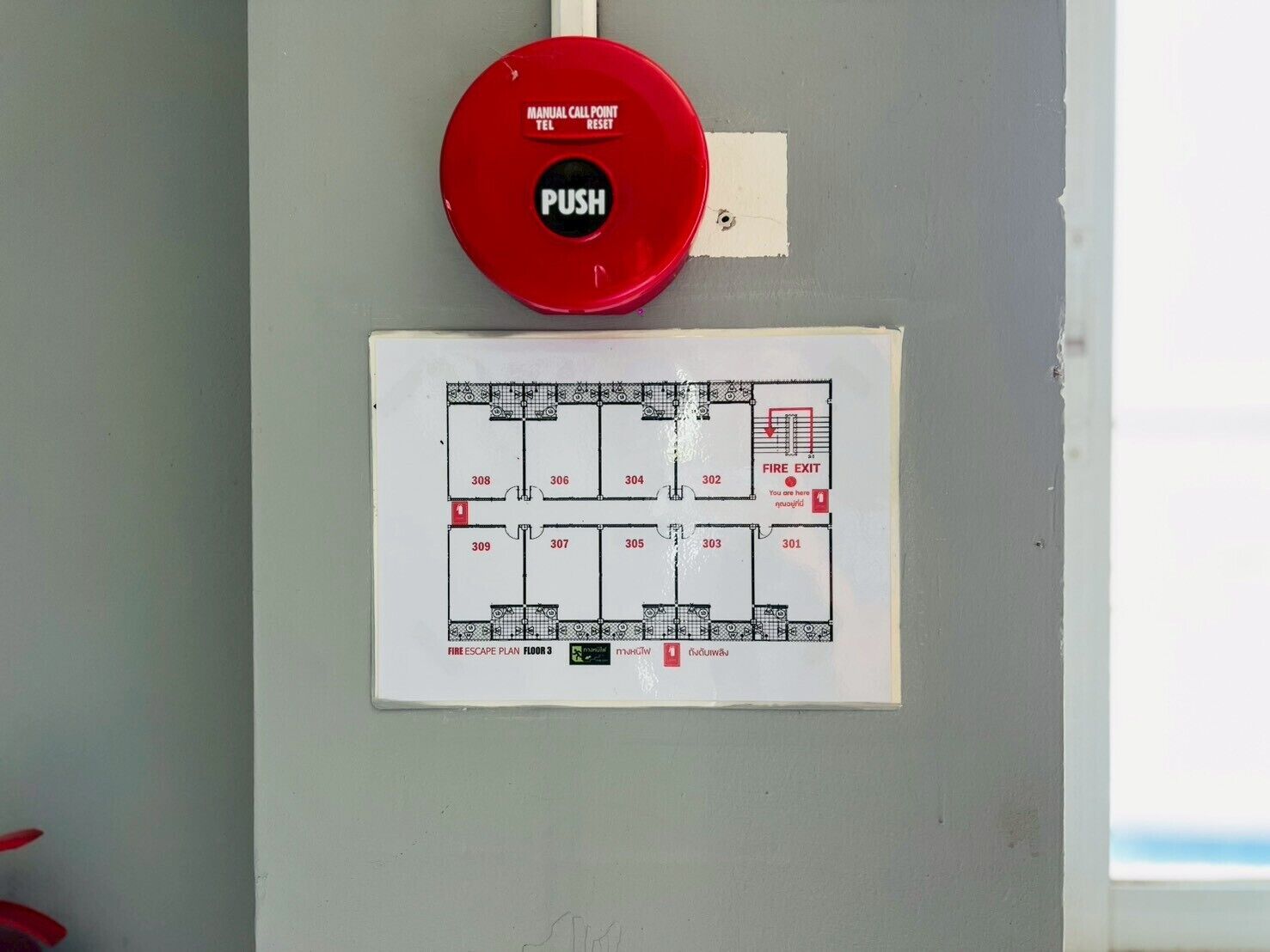Un botón de alarma de incendios y un plano de evacuación en una pared.