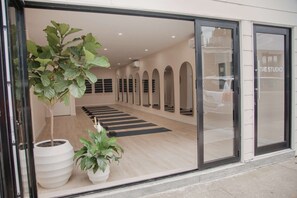 A modern interior with a yoga mat area, large mirrors, and potted plants. - Rockaway Beach Stay | Pool. Rooftop. Dining + Spa (Queens)