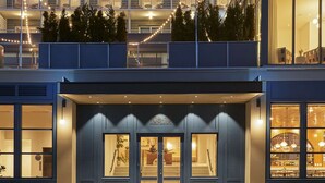 Un hôtel à plusieurs étages, doté d’un design moderne, avec des balcons, de grandes fenêtres et une entrée bien éclairée.