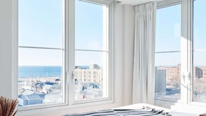 Une chambre à coucher avec un grand lit, une vue sur la ville et une fenêtre avec des rideaux.