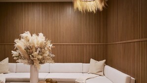 Un salon moderne avec un canapé d’angle, une table basse et un vase décoratif contenant des fleurs séchées.