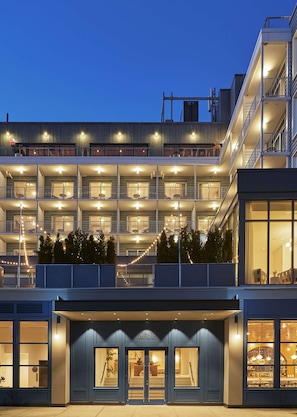 Un hotel de varios pisos con balcones, una entrada visible y una fachada bien iluminada.