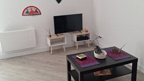 Een woonkamer met een televisie, een salontafel en decoratieve ventilatoren aan de muur.