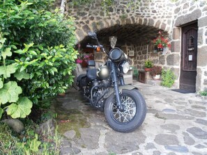 A motorcycle parked in front of a stone building with a rustic entrance.
