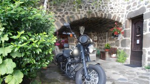 A motorcycle parked in front of a stone building with a door and windows. - Guest Room 'Chambre Rivage' with Shared Terrace & Garden, Wi-Fi (Polignac)