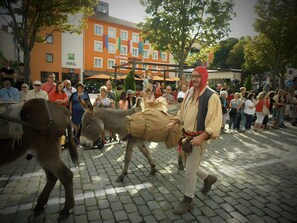 A street scene with a man leading a donkey, a crowd of people, and a building with a sign that reads 'HOTEL.' - Guest Room “Chambre Rêverie” with Shared Terrace, Garden and Wi-Fi (Polignac)