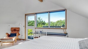 Quarto com uma janela grande, cama, escrivaninha e cadeira.